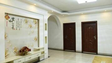 Un hall d’hôtel comprenant un comptoir d’accueil, deux portes en bois et un mur décoratif orné de calligraphies.