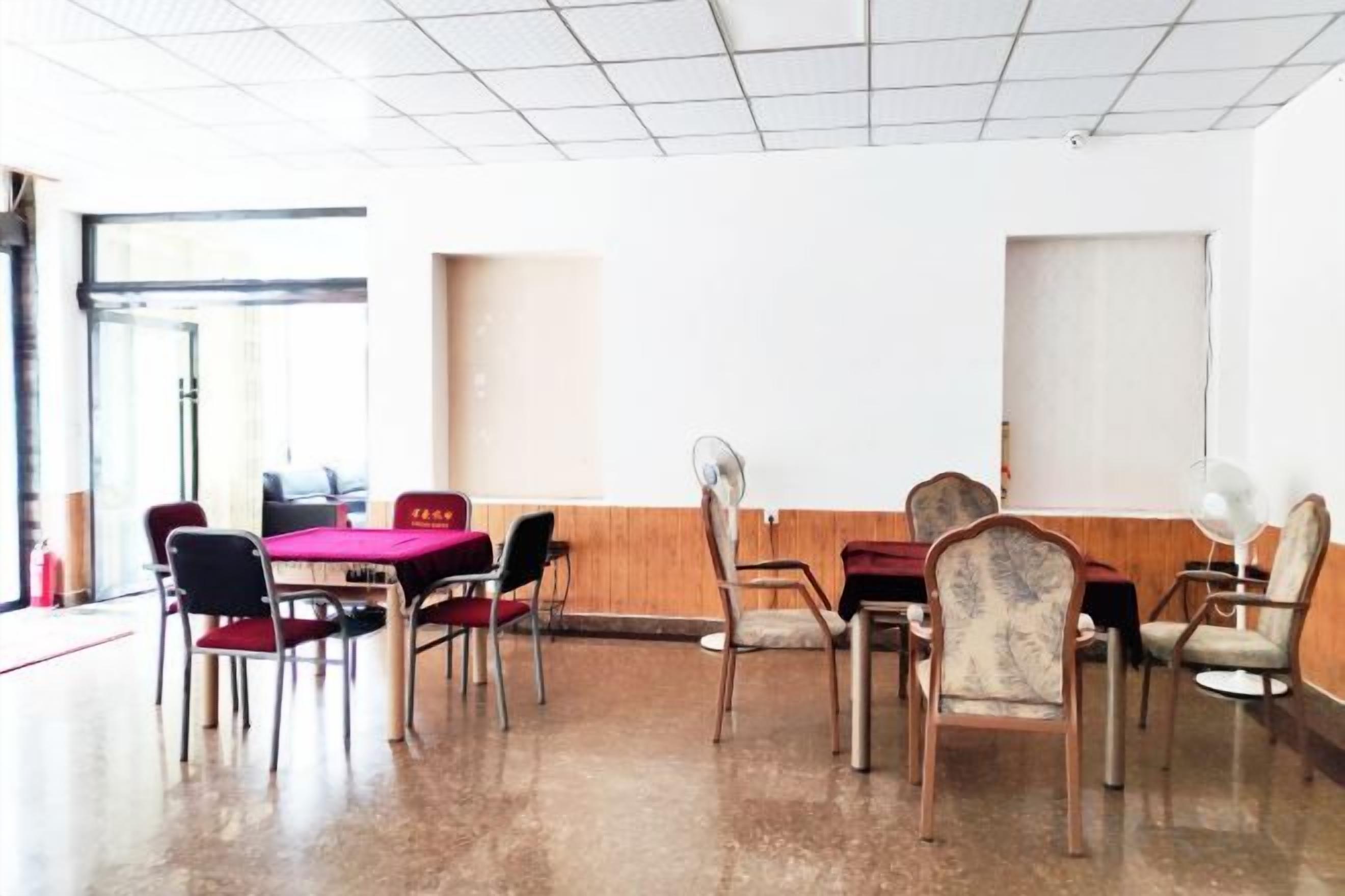 Una sala conferenze con tavolo e sedie, un ventilatore e una finestra.