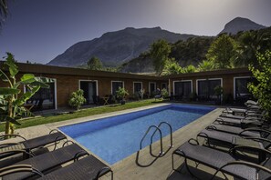 Ein Poolbereich mit Liegestühlen und Blick auf die Berge.