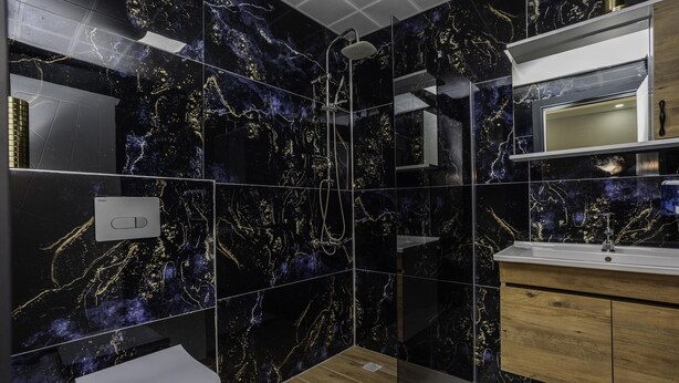 A modern bathroom with a black marble backsplash, a shower, a toilet, and a wooden vanity with a sink. - Terra Garden Hotel  (Kemer)