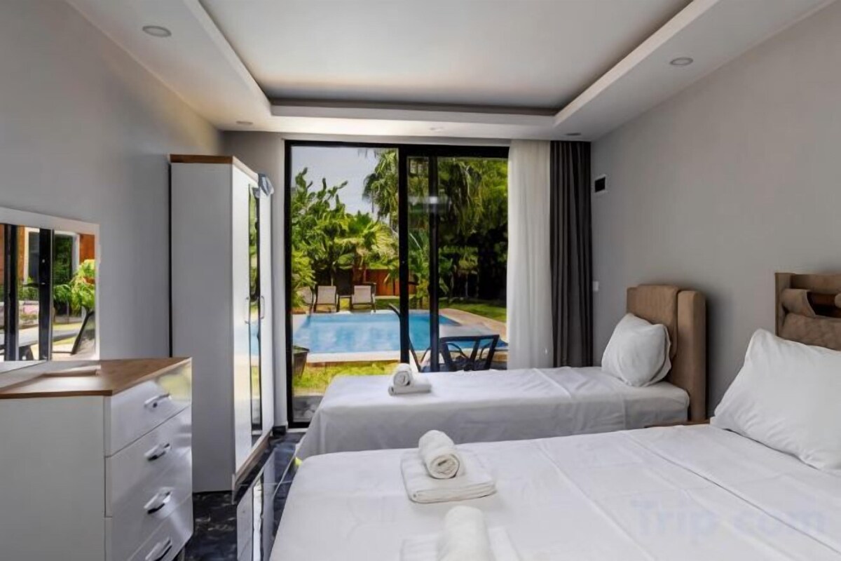 A hotel room with two beds, a desk, and a view of a swimming pool.