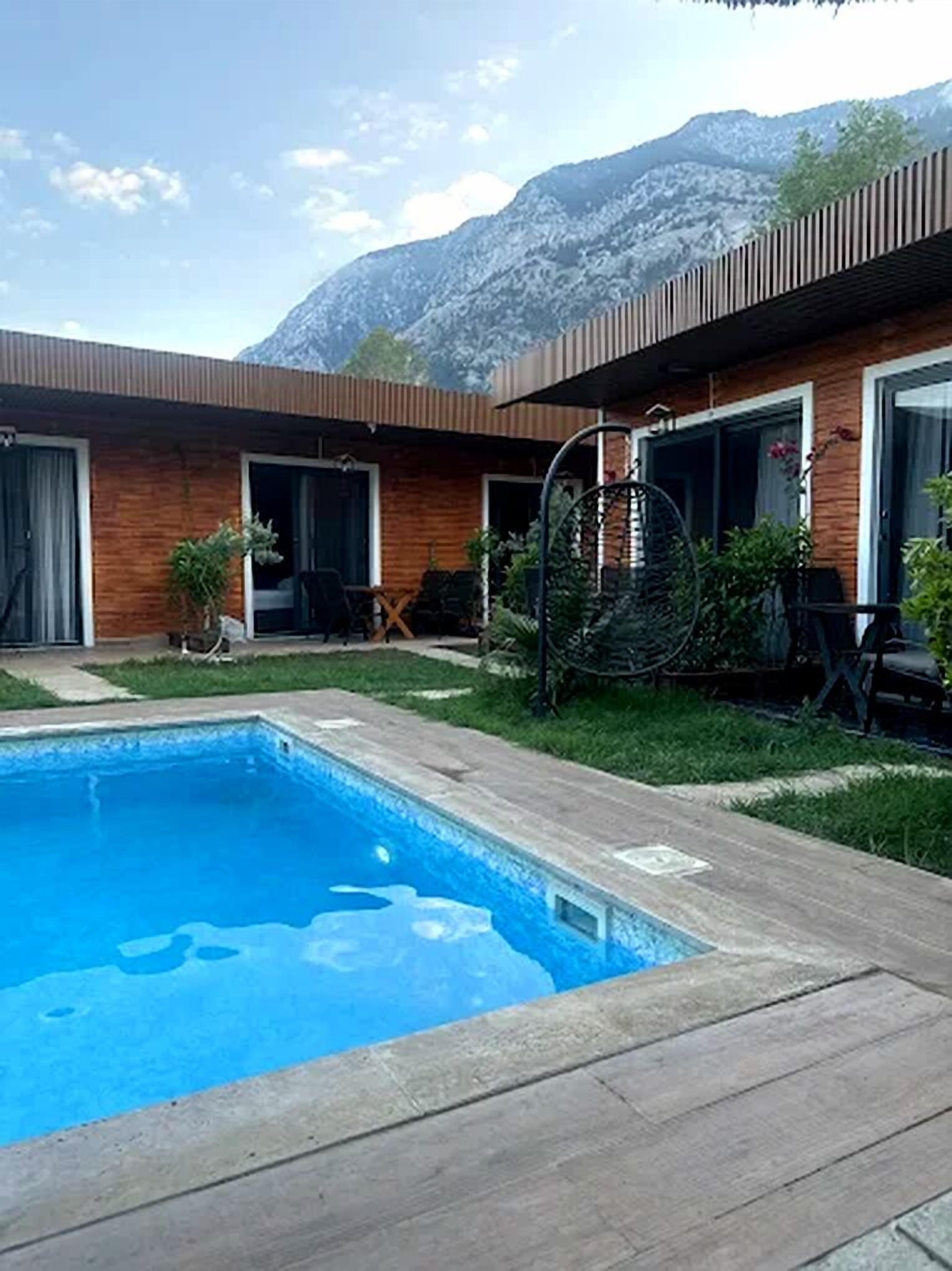 Una casa moderna con piscina, fachada de madera y vistas a la montaña.