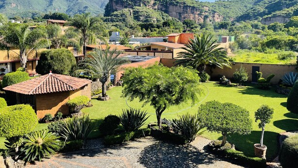 A residential area with houses, a well-maintained garden, and a mountainous backdrop. - Casa Akbal (Malinalco)