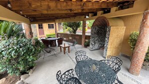 An outdoor patio with a round metal table and chairs, surrounded by potted plants and a brick wall. - Casa Akbal (Malinalco)