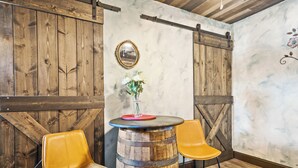 A rustic interior with wooden walls, a round wooden barrel table, and two yellow chairs.