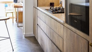 A modern kitchen with wooden cabinetry, a stainless steel oven, and a visible Siemens brand appliance. - Cosy Victorian house in south London with a sunny private garden. (LONDON)
