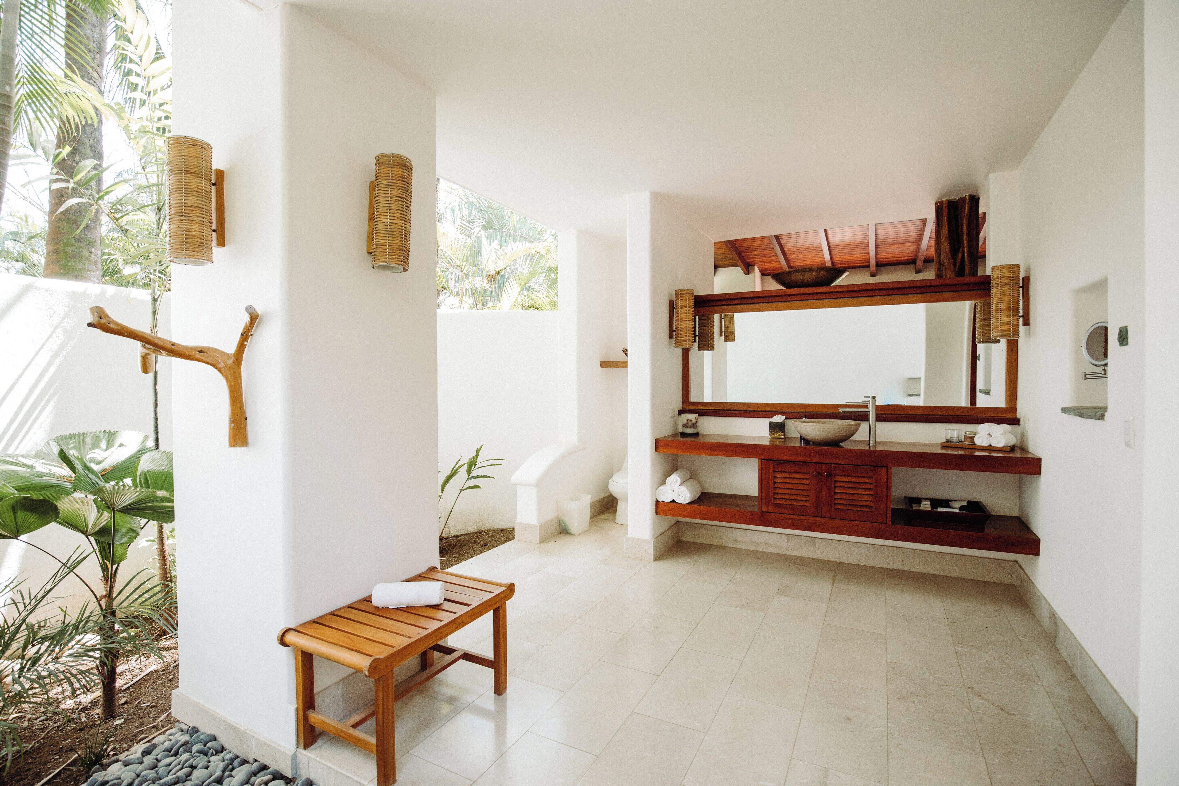 A bathroom with a wooden bench, a large mirror, and a sink.