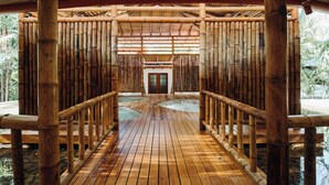 A wooden deck with a bamboo railing, leading to a door at the end. - FLORBLANCA HOTEL  (Cóbano)
