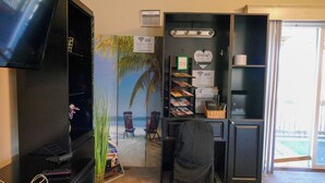 Une pièce dotée d’un grand téléviseur à écran plat, d’un bureau avec un ordinateur, d’une chaise et d’une bibliothèque contenant des magazines.