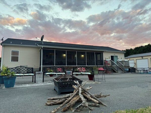 A two-story building with a covered porch, outdoor seating, and a fire pit.