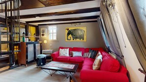 A cozy living room with a red sofa, a small table, and a decorative elephant painting on the wall.