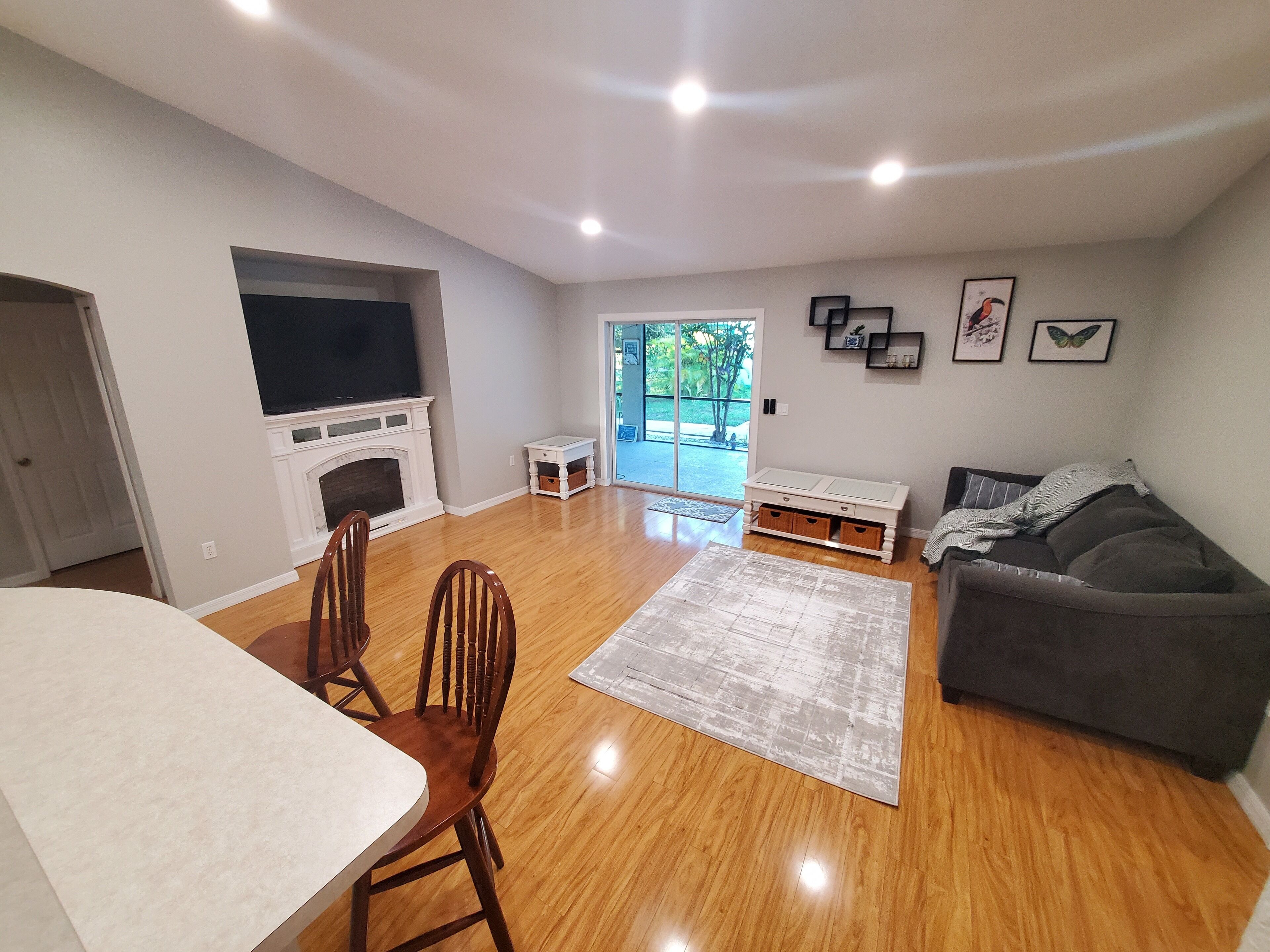 A spacious living room with a fireplace, a television, a sofa, and a dining area with chairs.