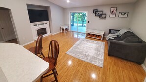 Uma sala de estar ampla com lareira, televisão, sofá e um espaço de refeições com cadeiras.