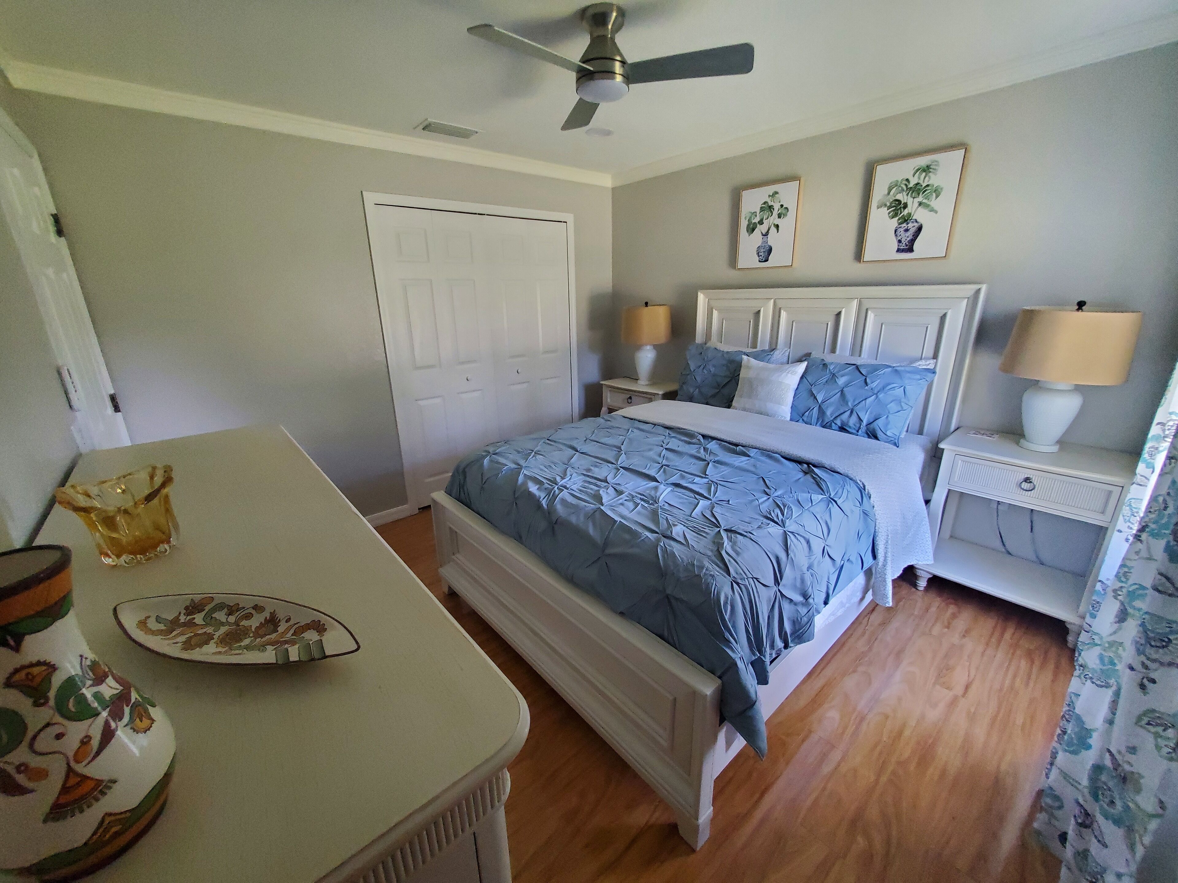 A bedroom with a bed, bedside tables, a ceiling fan, and a door.