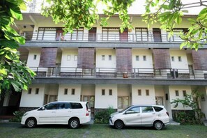 A multi-story building with a parking area in front. - Urbanview Hotel Wayan Mansion (Bali)