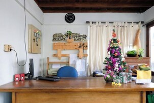 Un escritorio de madera con una computadora, un reloj y un árbol de Navidad.