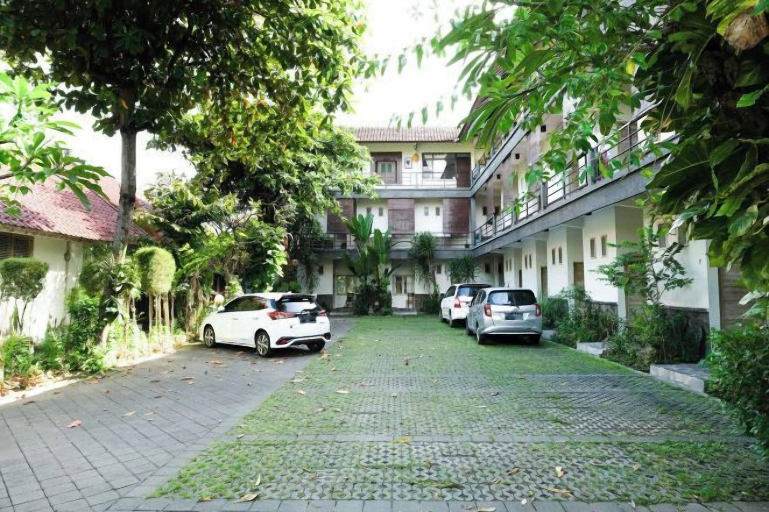 A courtyard with parked cars and a building with multiple floors and balconies.