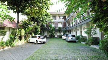A courtyard with parked cars and a building with multiple floors and balconies.