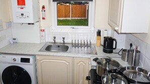 A kitchen with a washing machine, a sink, and a window with a view of a wooden fence. - Biz & Fam Sleeps 7 Wigan w/ Parking, Self-check-in (Wigan)