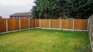 A fenced backyard with a grassy lawn and a tall tree. - Biz & Fam Sleeps 7 Wigan w/ Parking, Self-check-in (Wigan)
