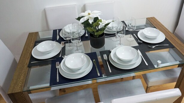 A dining table set with white plates, glasses, and cutlery, surrounded by white chairs. - Biz & Fam Sleeps 7 Wigan w/ Parking, Self-check-in (Wigan)