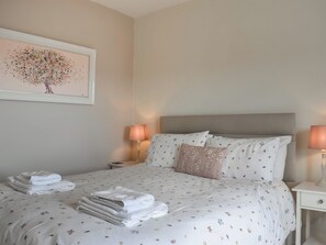 A neatly made bed with floral bedding, two bedside lamps, and a framed artwork on the wall. - 3 bedroom accommodation in Hinderwell, near Runswick Bay (Hinderwell, near Runswick Bay)