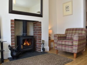 A cozy living room with a fireplace, a plaid sofa, and a mirror on the wall.