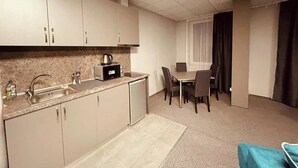 Una cocina compacta con un lavamanos, una cafetera y una zona de comedor con una mesa y sillas.