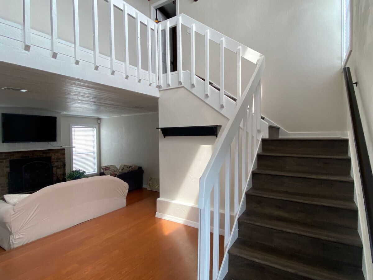 A spacious living area with a staircase leading to an upper floor.