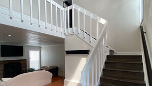 Un amplio salón con una escalera que sube a un piso superior.