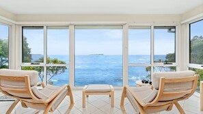 Enjoy breathtaking ocean views from the comfort of your room, featuring a large window and two lounge chairs.