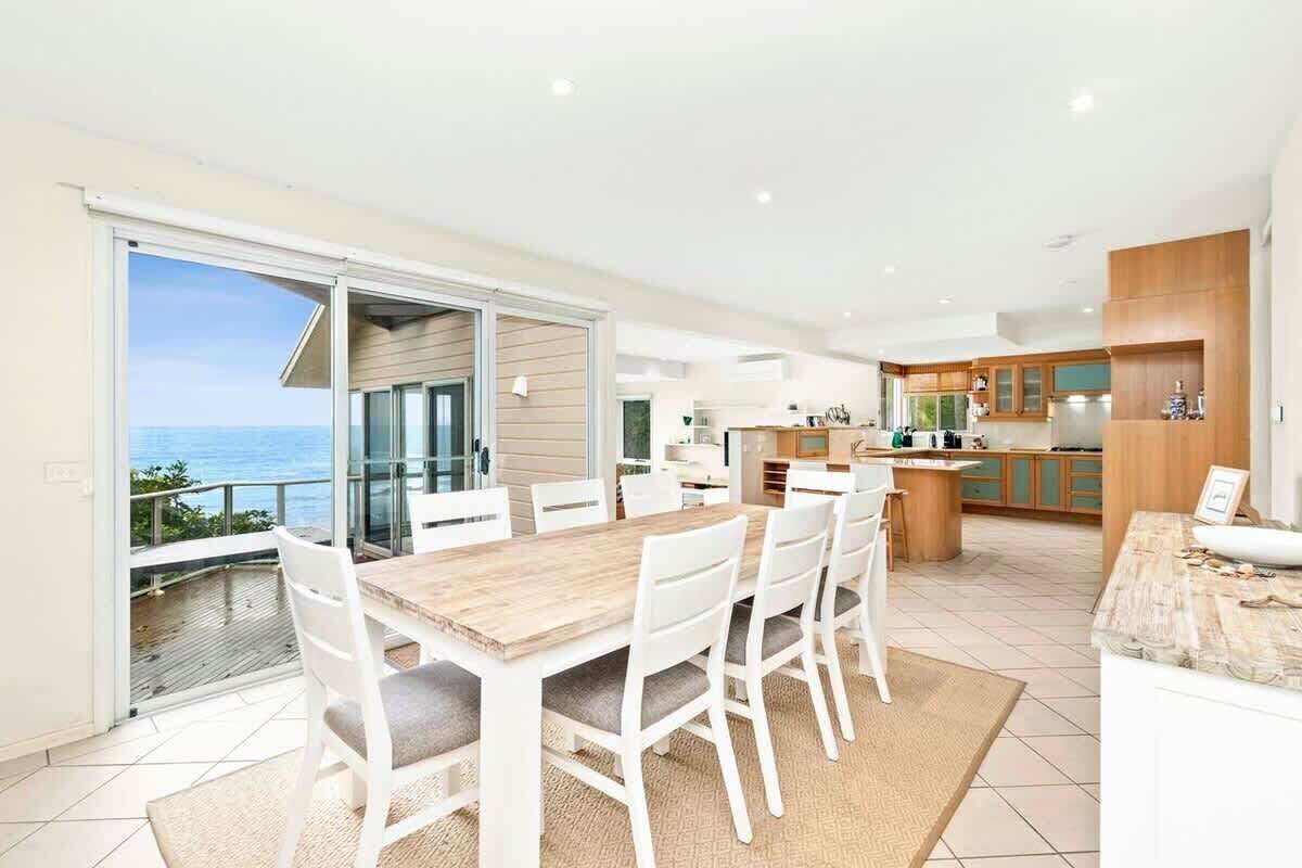 A modern kitchen with wooden cabinets and a dining area with a large table and chairs.