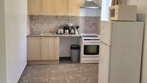A compact kitchen with wooden cabinets, a microwave, a stove, and a refrigerator.