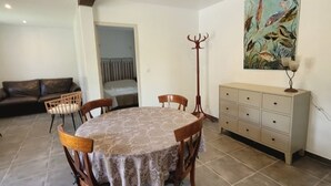 A dining area with a round table, chairs, a cabinet, and a painting on the wall.