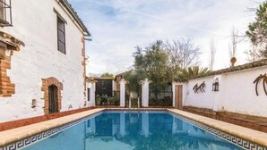 A pool area with a white building, a brick wall, and a clear sky. - Casa Rural con Encanto Coronel Cordoba Andalusia (Fuente Obejuna)