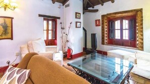 A cozy living room with a glass coffee table, a sofa, and a fireplace. - Casa Rural con Encanto Coronel Cordoba Andalusia (Fuente Obejuna)