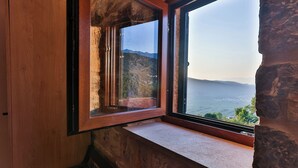 A room with a stone wall, a wooden door, and a window overlooking a mountainous landscape. - Boutique hotel Ruzmarin Garden&SPA (Budva)
