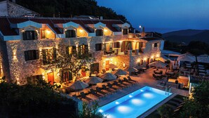 A stone building with a swimming pool, outdoor seating, and a view of the hills. - Boutique hotel Ruzmarin Garden&SPA (Budva)