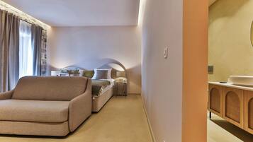 Una habitación de hotel moderna con sofá, una mesita de noche pequeña, lámpara y un mueble de madera.