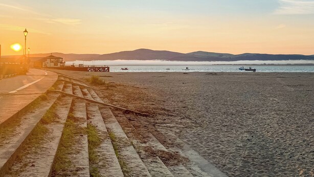 A beach with a pier, boats, and a sunset. - Tranquil lodge with sea views. (Plas Panteidal, near Aberdovey)