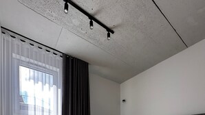 A modern bedroom with a large bed, a smaller sofa, and a window with sheer curtains. - Apartamenty I SORAU Old Town (Zary)