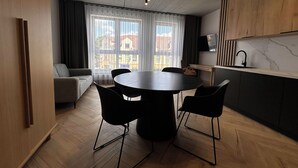 A modern kitchen with a dining area, wooden cabinets, and a large window with curtains. - Apartamenty I SORAU Old Town (Zary)