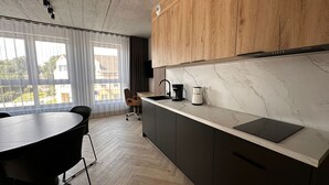 A modern kitchen with wooden cabinets, a marble countertop, and a view of the outdoors through large windows. - Apartamenty I SORAU Old Town (Zary)