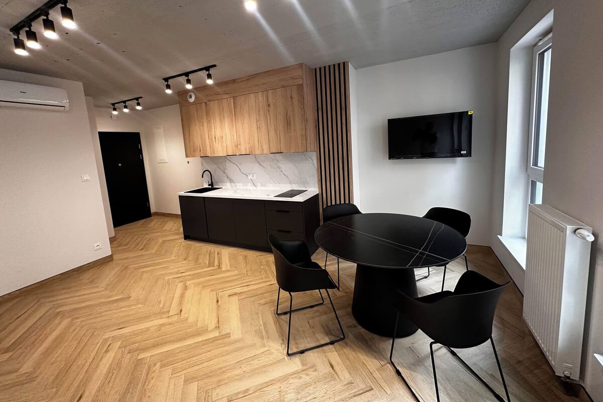 A modern kitchen with a central island, black chairs, and a dining table.