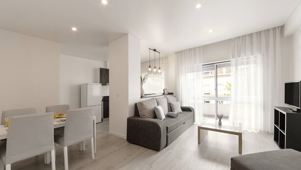 A modern living room with a sofa, dining table, chairs, and a TV stand. - Nazaré Horizon - Balcony View (Nazaré)