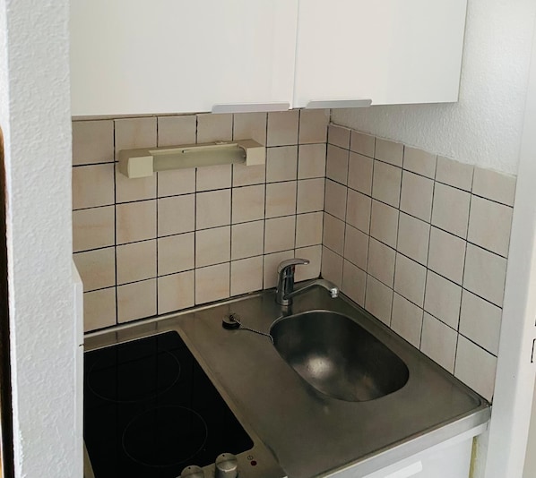 A small kitchen with a sink, a stove, and a cabinet.