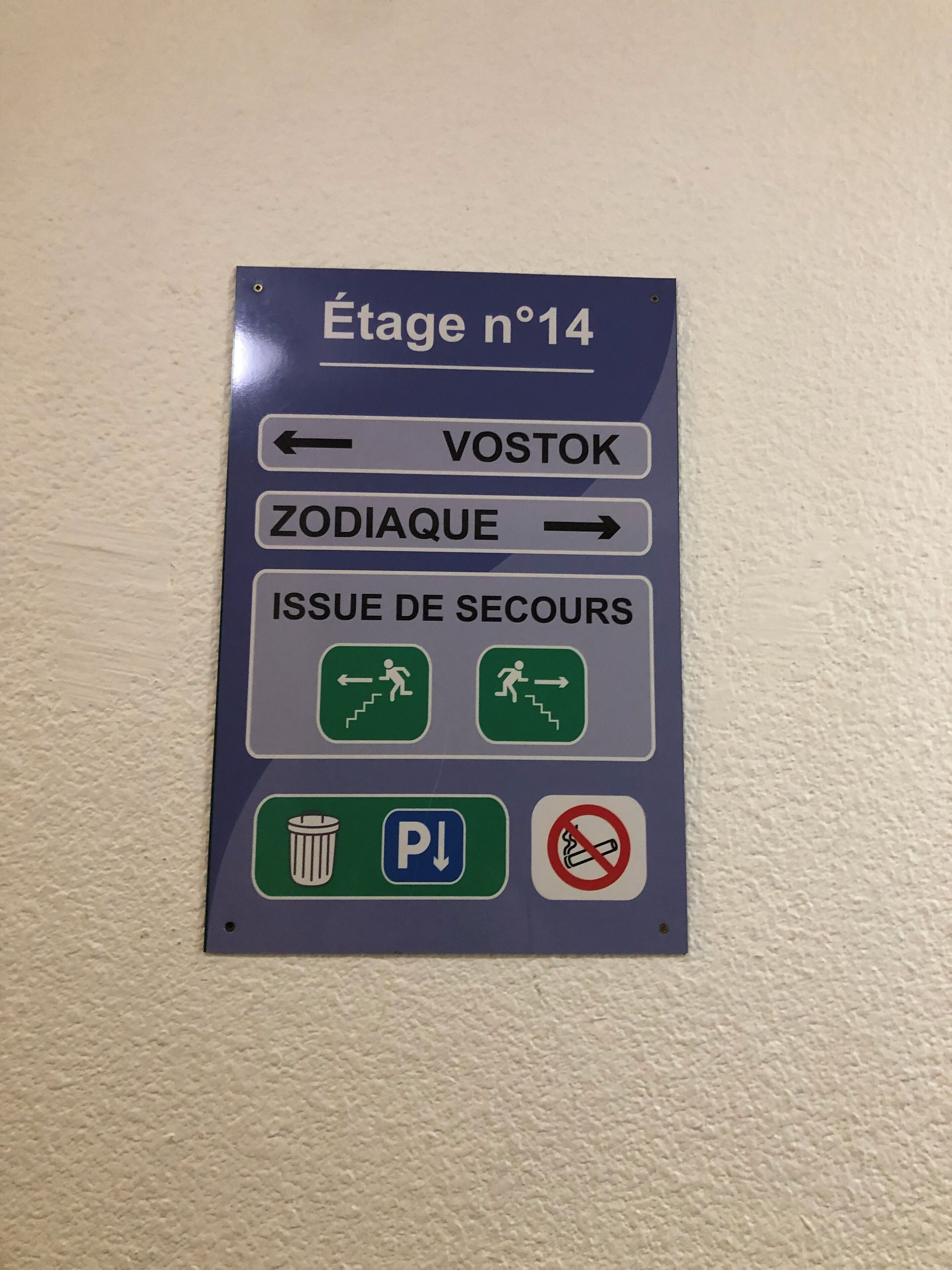 Een richtingwijzer met pijlen naar VOSTOK en ZODIAQUE, en symbolen voor een prullenbak, parkeerplaats en rookverbod.