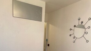 A small, clean room with a white table and chairs, a wall-mounted light fixture, and a door. - Studio Corbier Zodiaque Pool and Ski at the foot of the slopes  (Villarembert)
