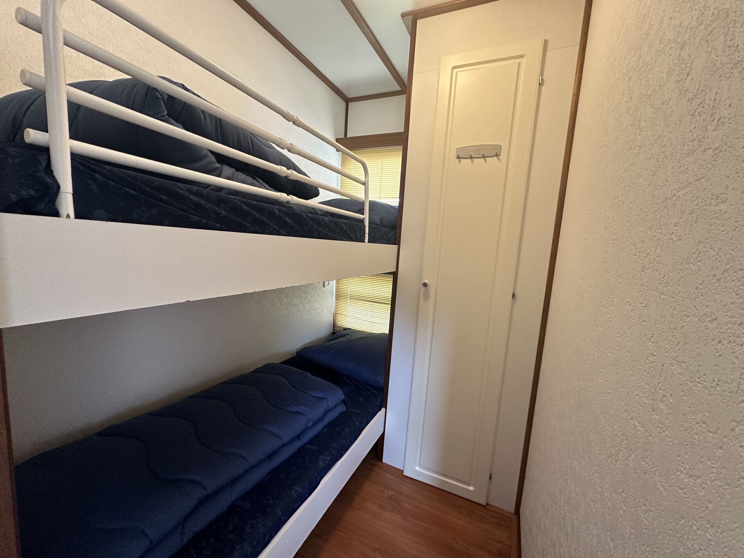 Habitación con literas, una puerta y una ventana con persianas.