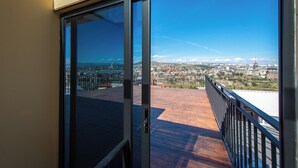 Een balkon met uitzicht op de stad, een glazen deur en een houten terras.